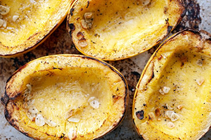 A close up of baked spaghetti squash on a baking sheet just out of the oven.