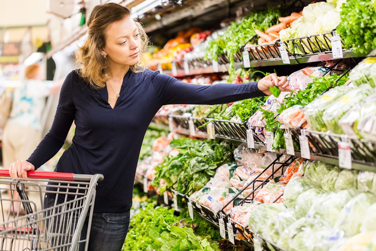 Young woman shopping in the fresh produce section at the grocery store.