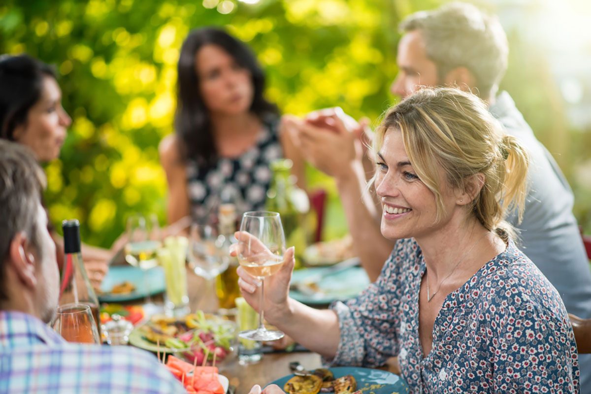 Group of friends gathered around a table on a terrace in the summer to share a meal