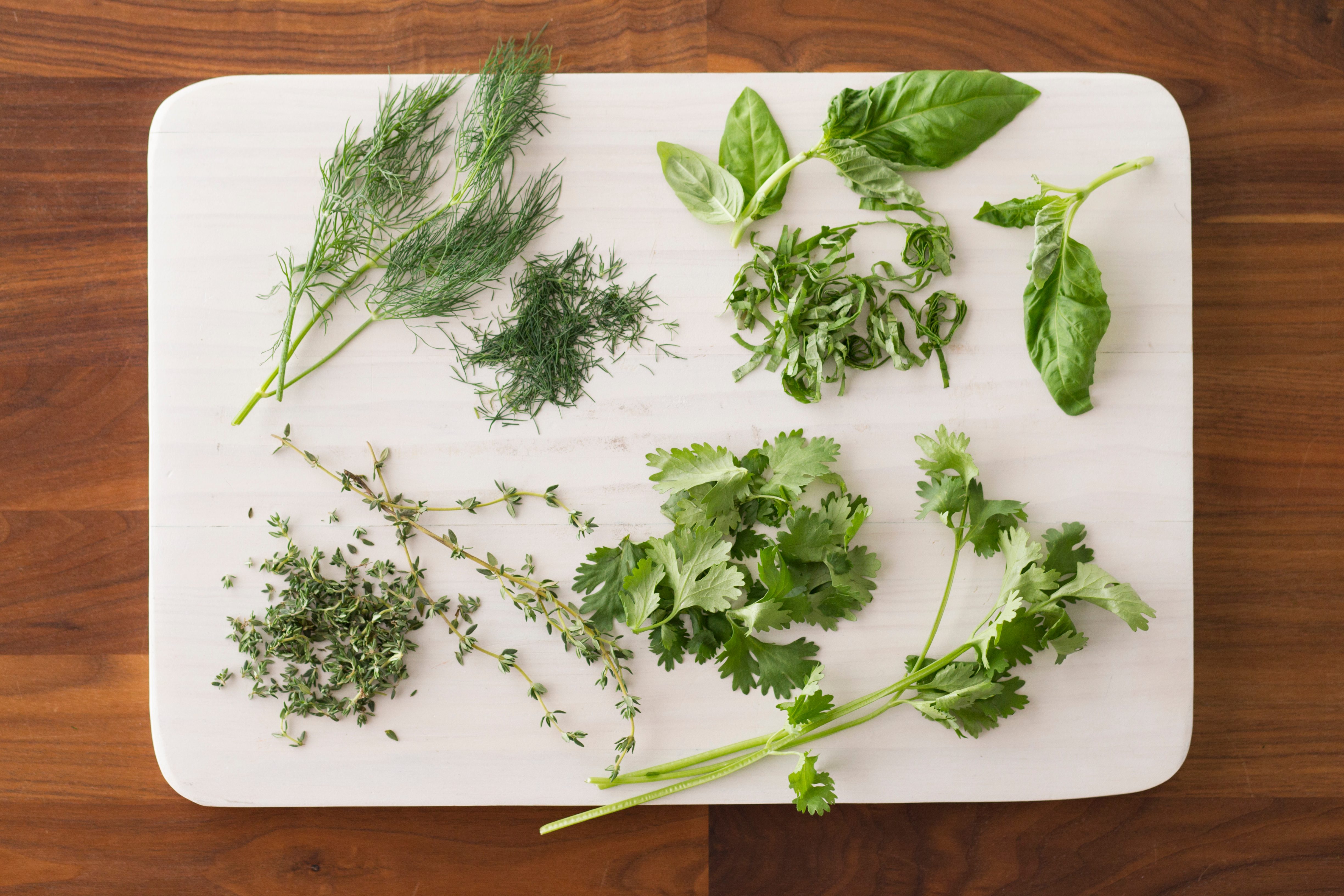 Chopped herbs spread out over a white cutting board