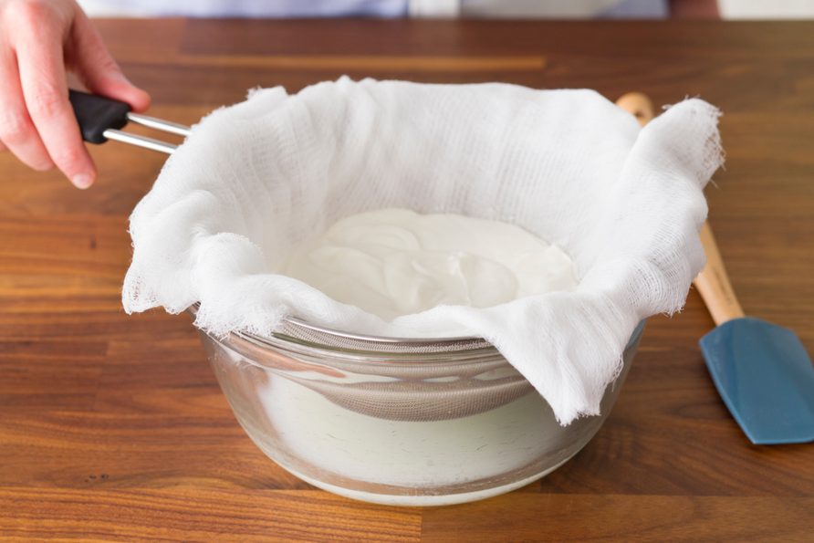 Lined strainer filled with Greek yogurt