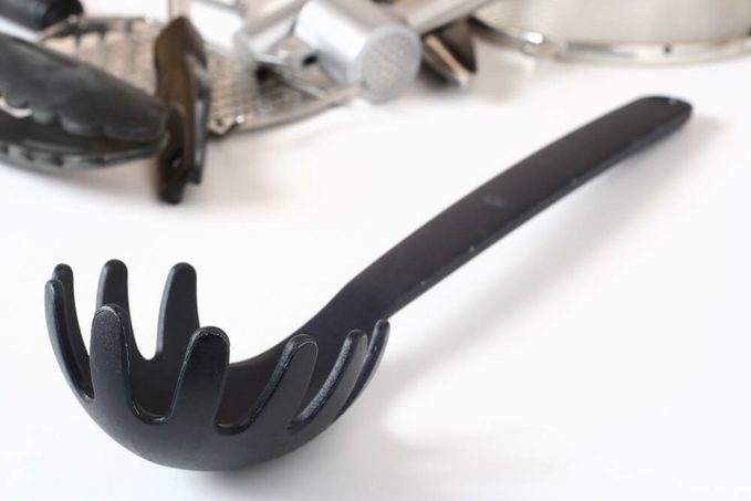 Pasta scoop and other kitchen utensils in the background