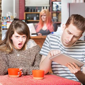 Insulted woman at table with young man using tablet
