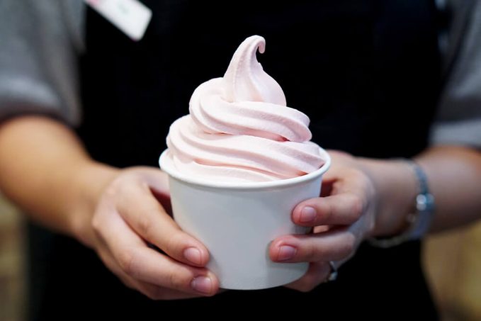Closeup of woman's hands holding cup with organic frozen yogurt Ice cream served in a plastic takeaway