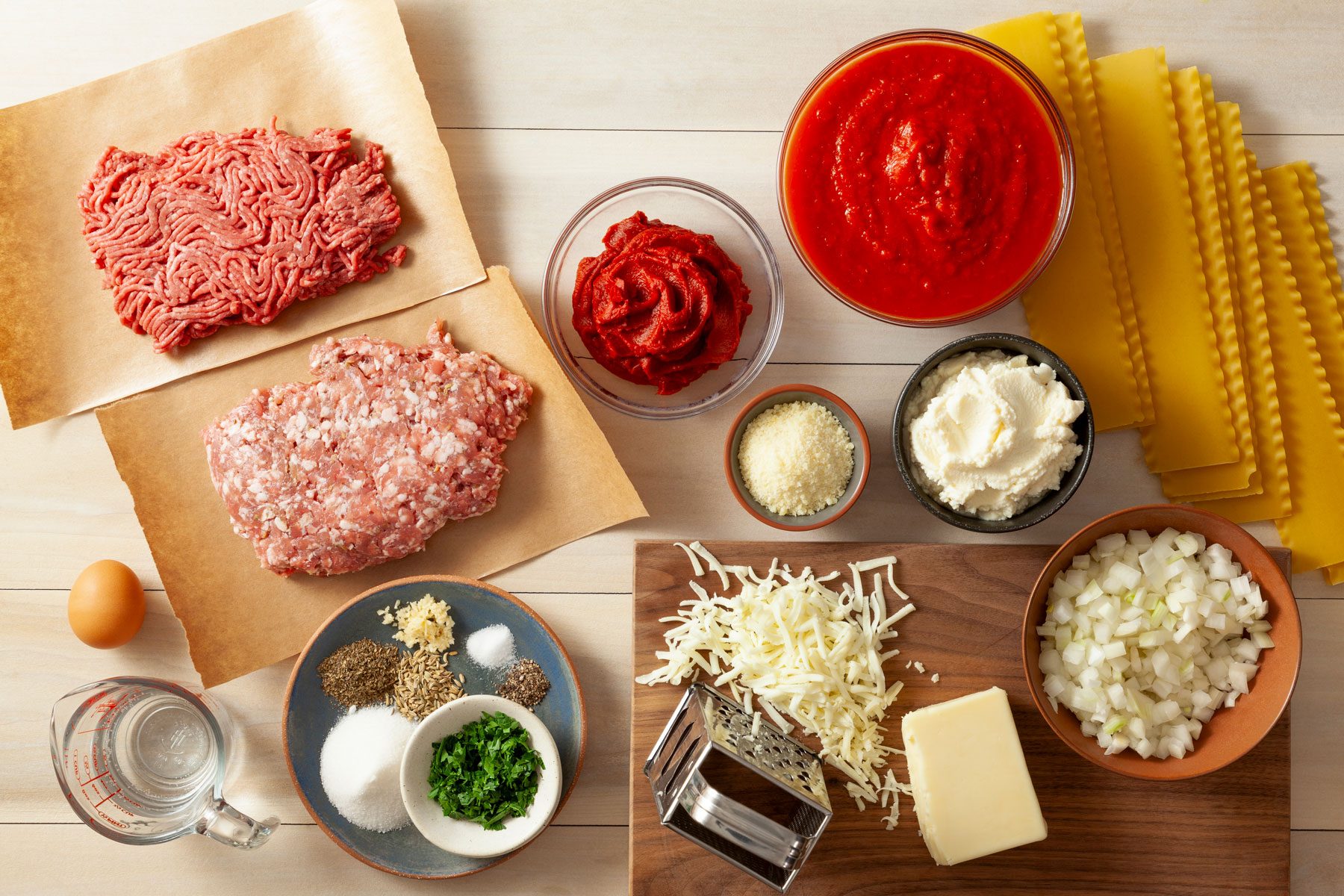 Lasagna noodles Sausage and ground beef and other ingredients arranged on a table