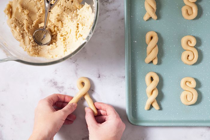 A person rolling flour balls into different shapes