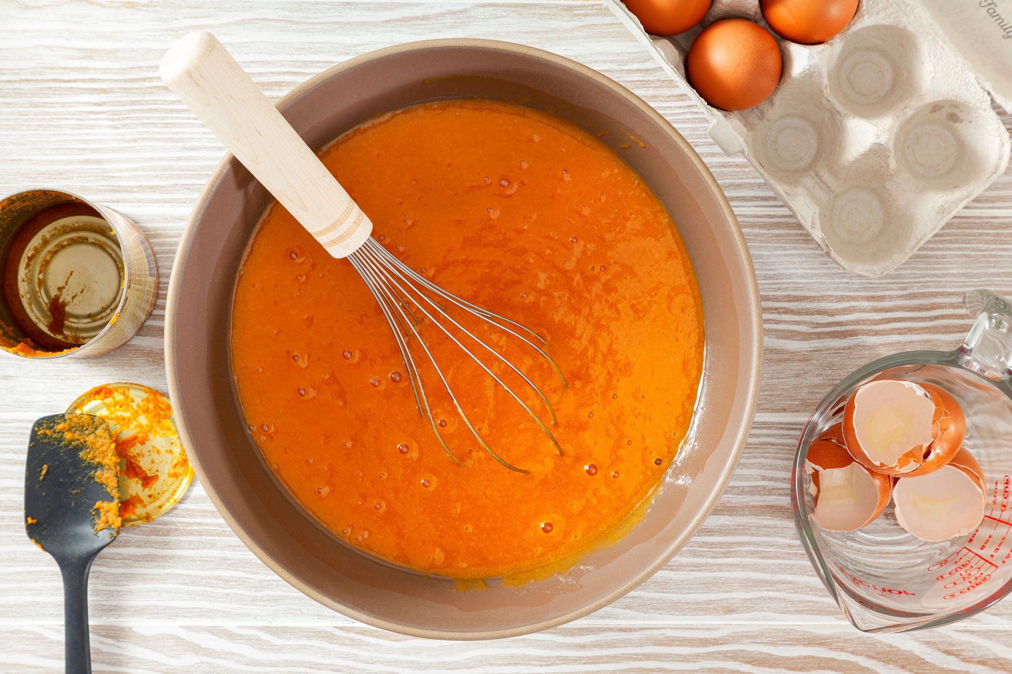 Mixing Wet Ingredients In A Large Bowl on Wooden Surface to Make Pumpkin Chocolate Chip Muffins