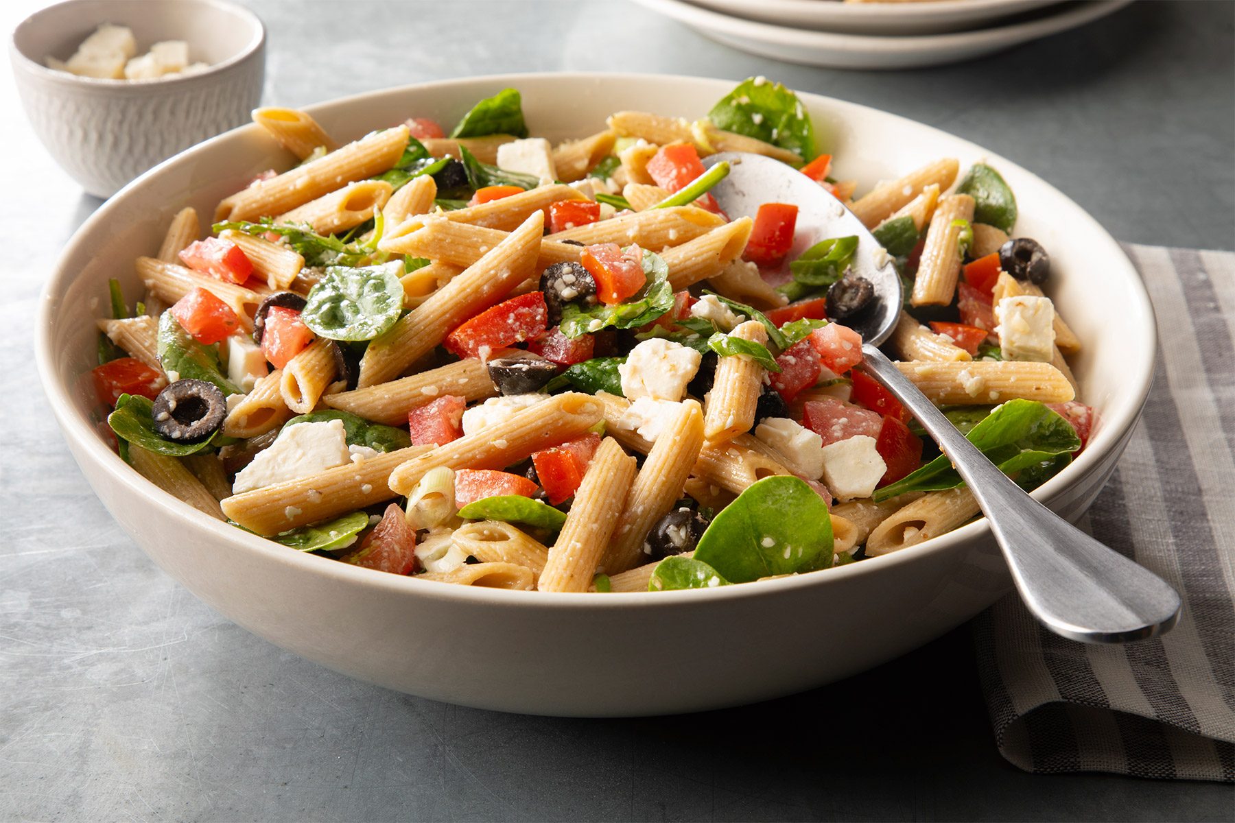 Spinach Pasta Salad in white bowl on grey surface