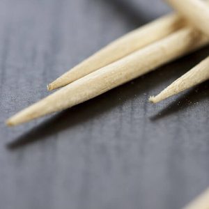 Pile of wooden toothpicks scattered randomly on a grey background for cleaning between the teeth after a meal in a personal hygiene concept