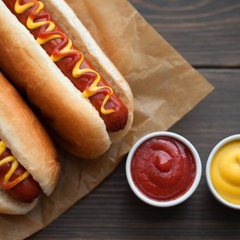 Barbecue Grilled Hot Dog with Yellow Mustard and ketchup on wooden table