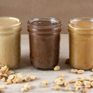 Peanut butter, hazlenut spread, and cashew butter on a wooden table