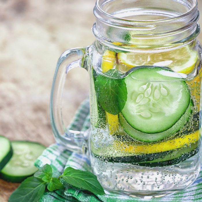 Detox Infused water with cucumber and lemon on wooden background