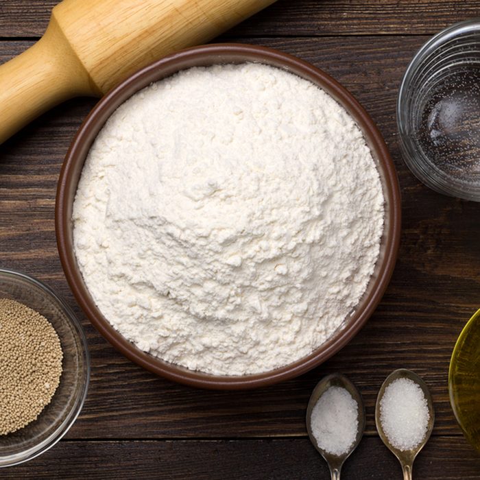 Ingredients for homemade pizza dough on dark rustic background.