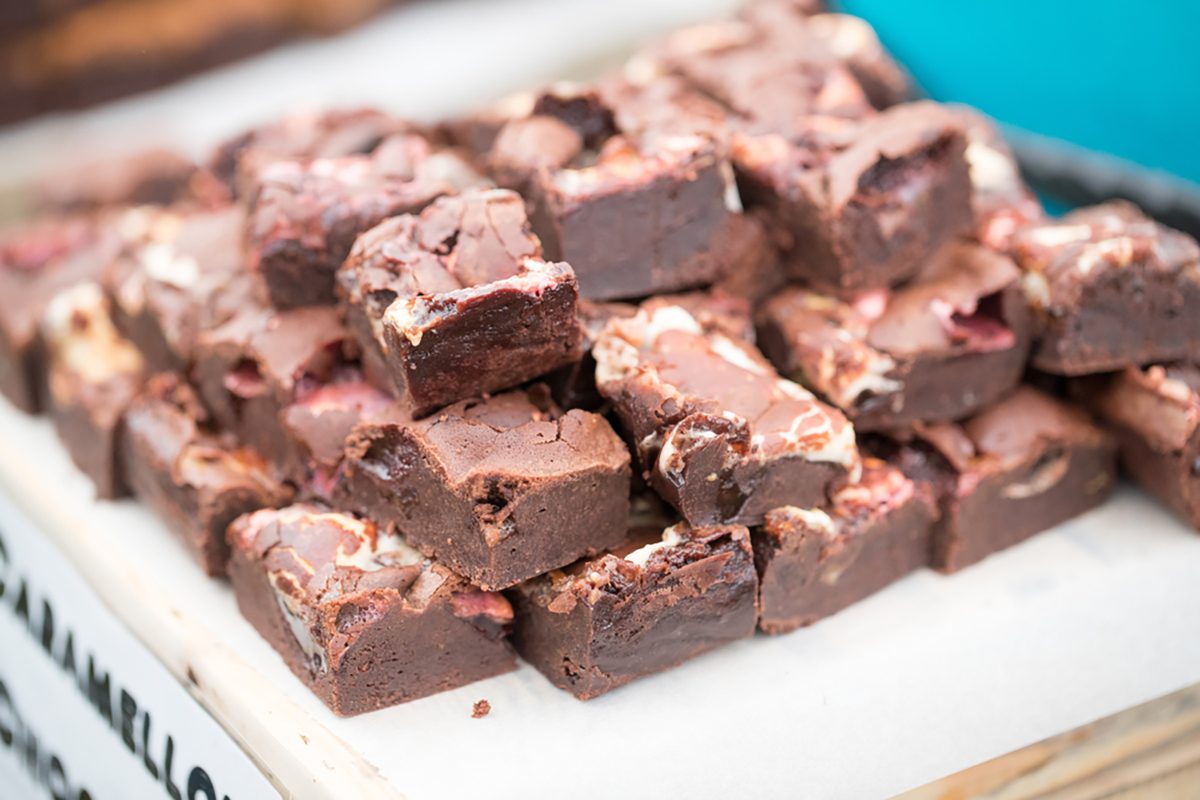 Gooey and delicious chocolate brownies neatly stacked for sale on a market stall at a food festival.