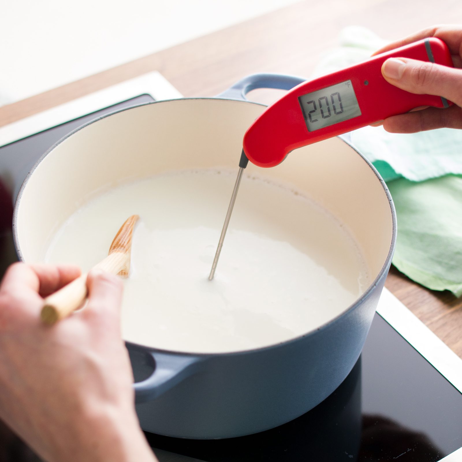 testing temperature of milk with a red thermometer