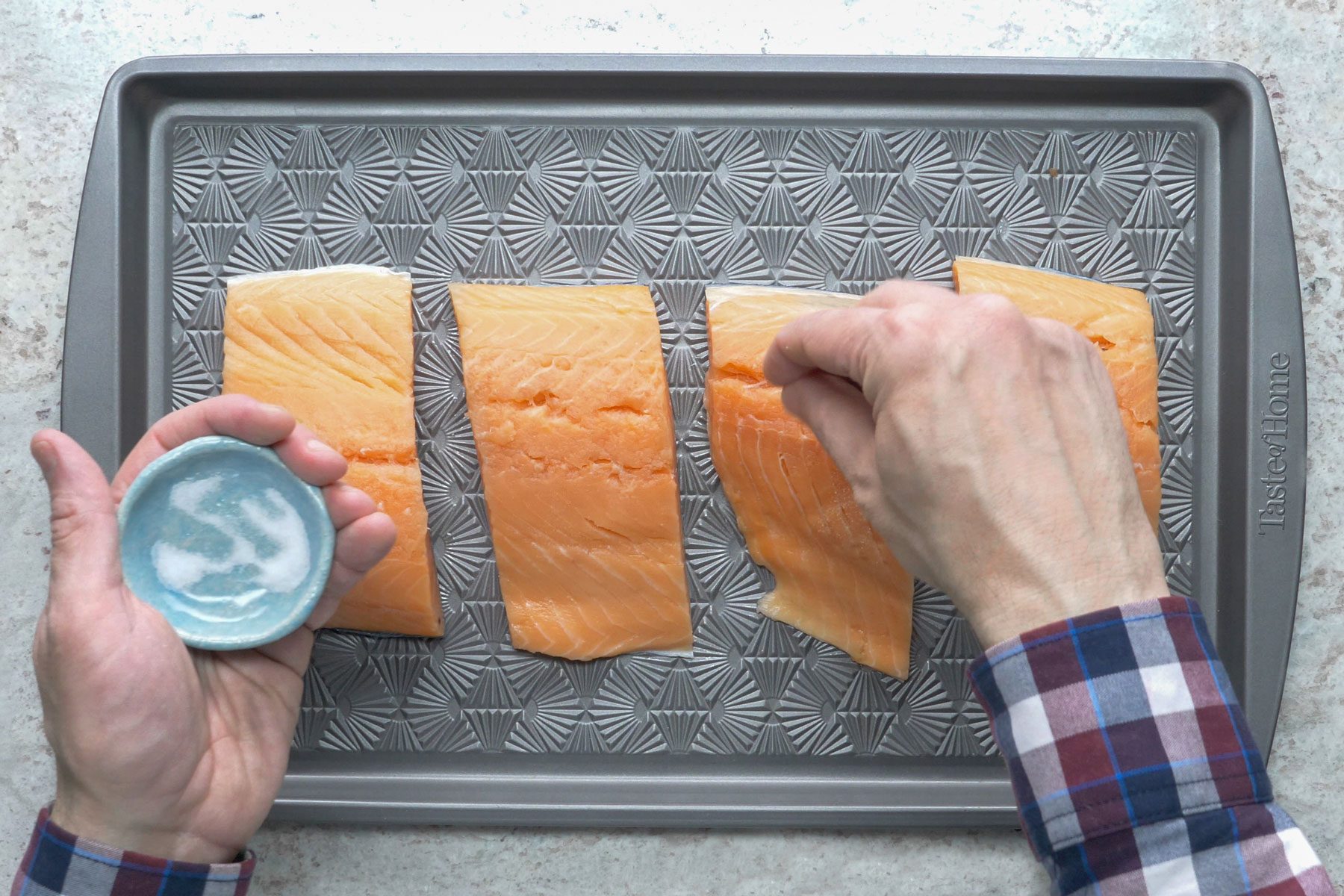 A person sprinkling salt on Salmon