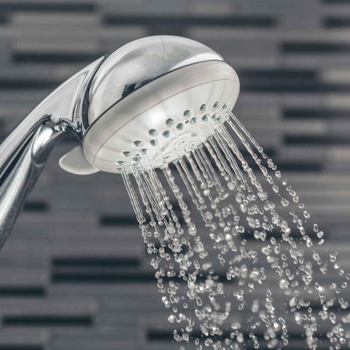 Shower head with water drops falling on a bathroom