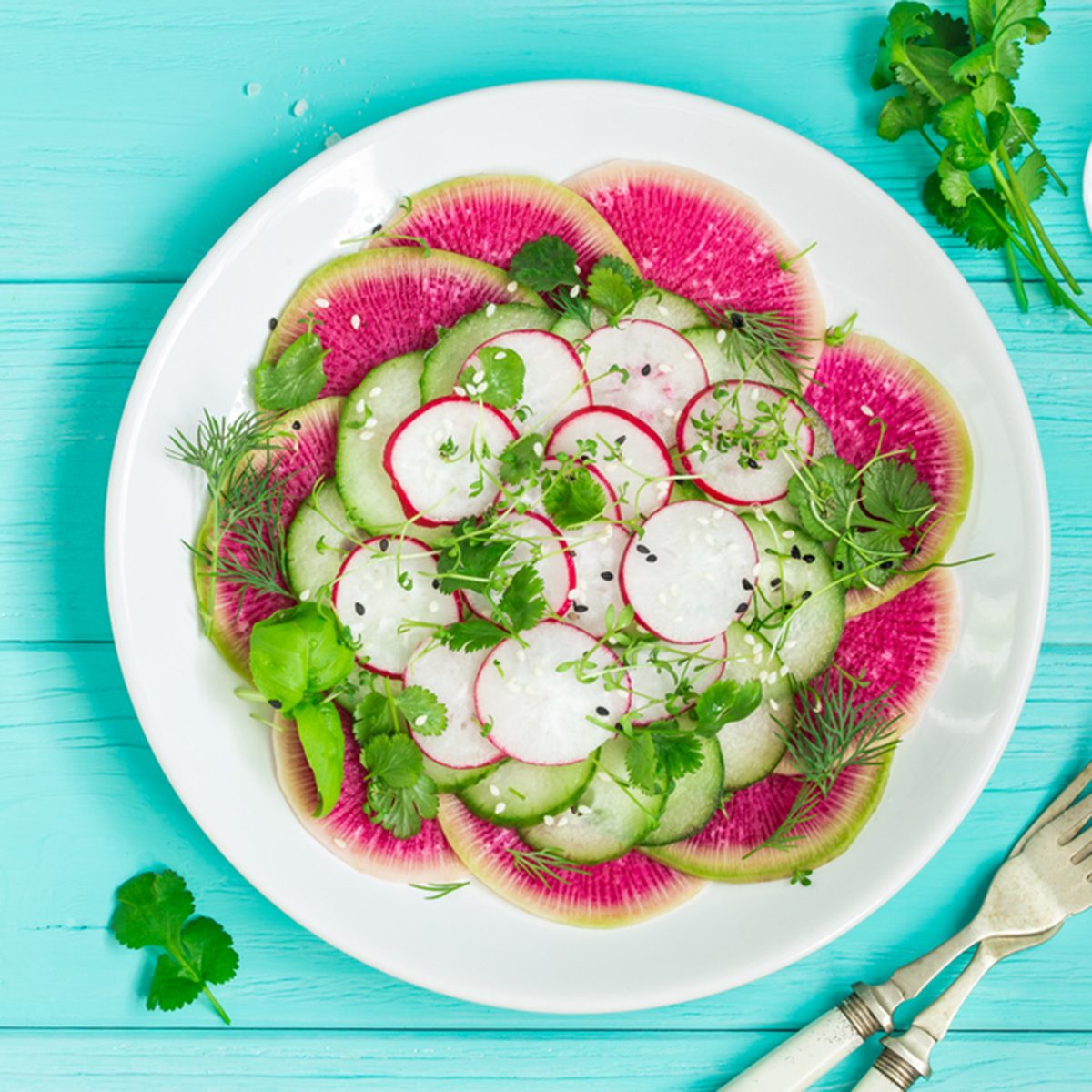 healthy vegan food. watermelon radish, cucumber and radish salad on white plate