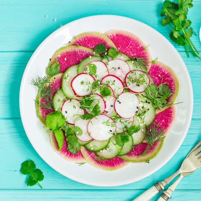 healthy vegan food. watermelon radish, cucumber and radish salad on white plate