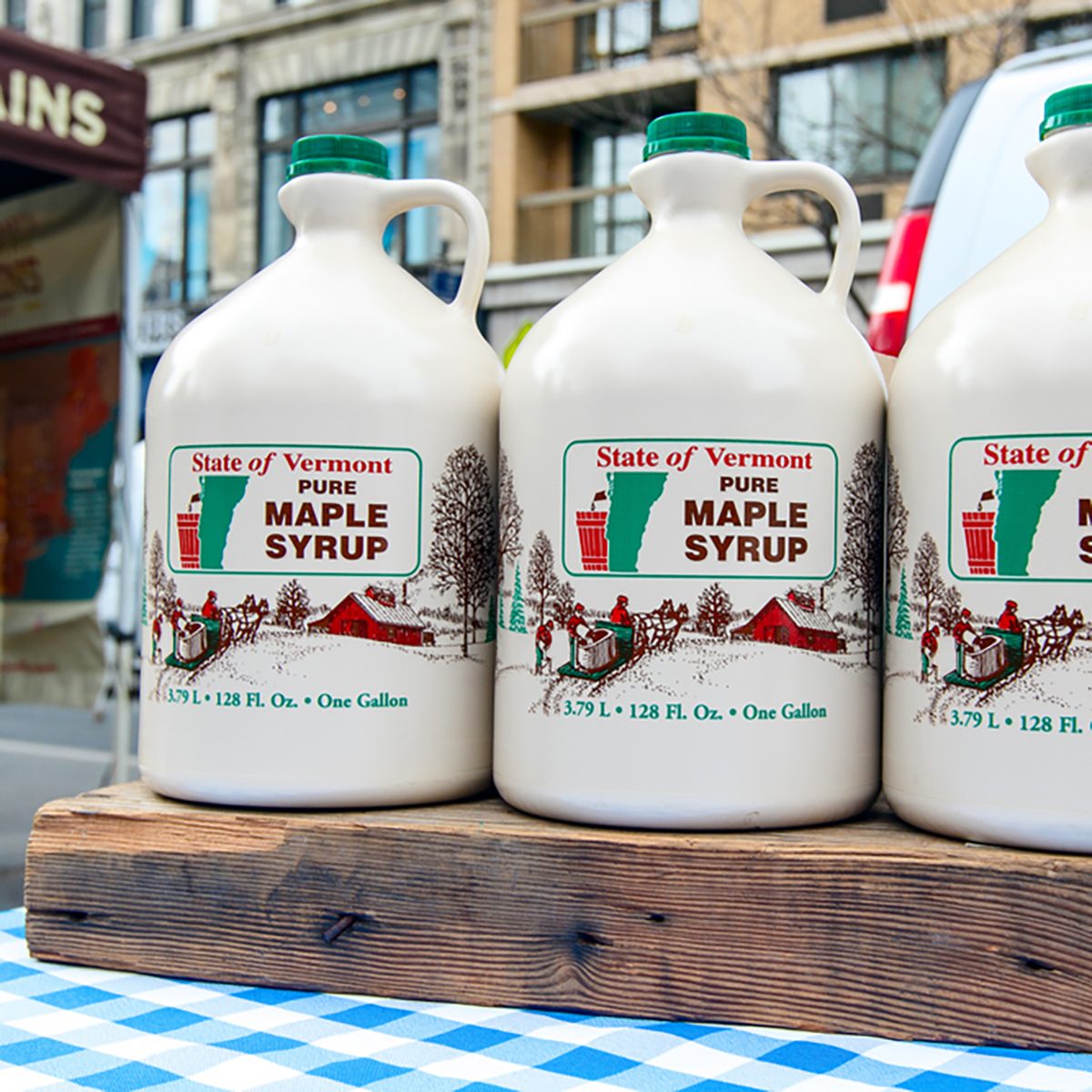 Jugs of Vermont maple syrup stand for sale at a farmer
