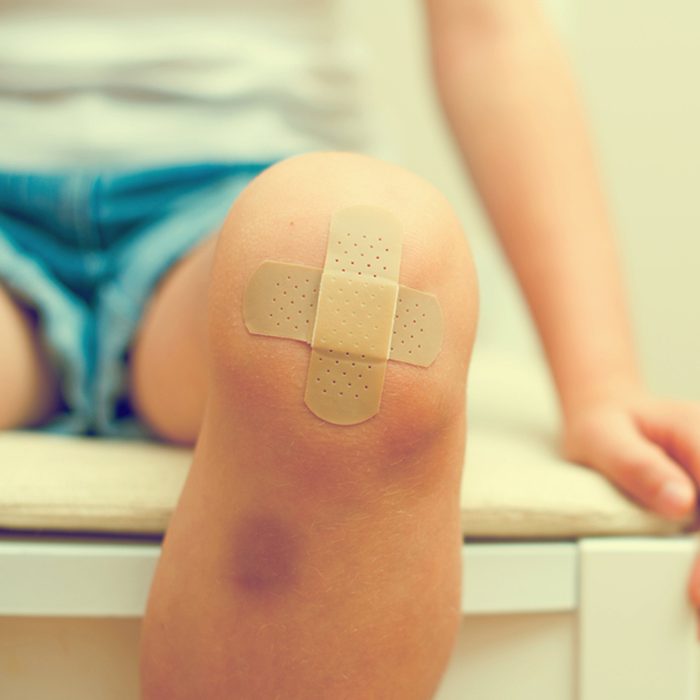 Child knee with an adhesive bandage and bruise.
