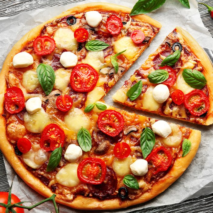 Fresh pizza with tomatoes, cheese and mushrooms on wooden table closeup