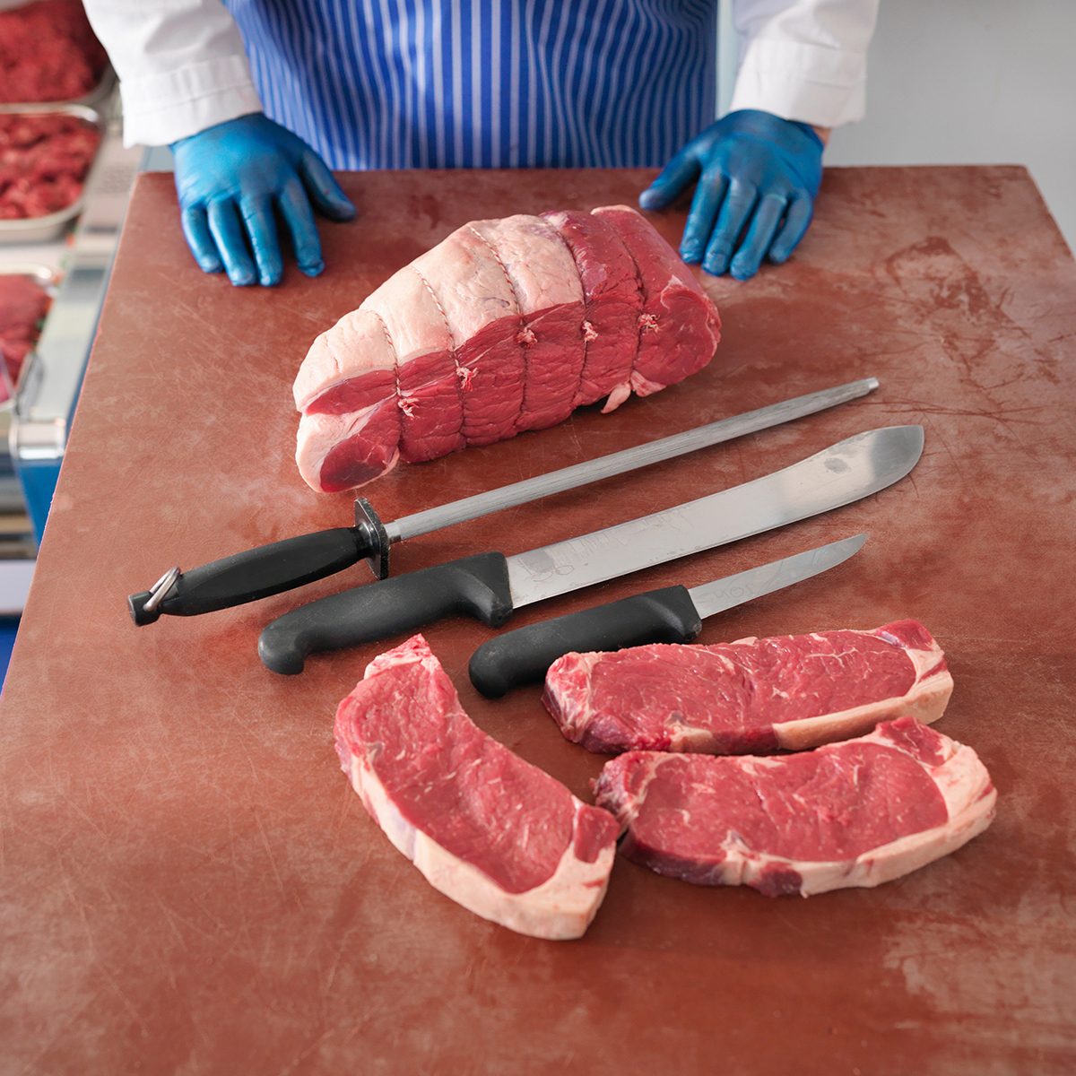 Butcher with knives and cuts of pork