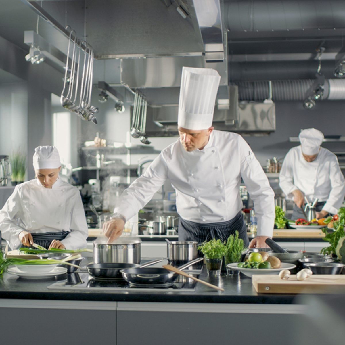 Famous Chef Works in a Big Restaurant Kitchen with His Help.