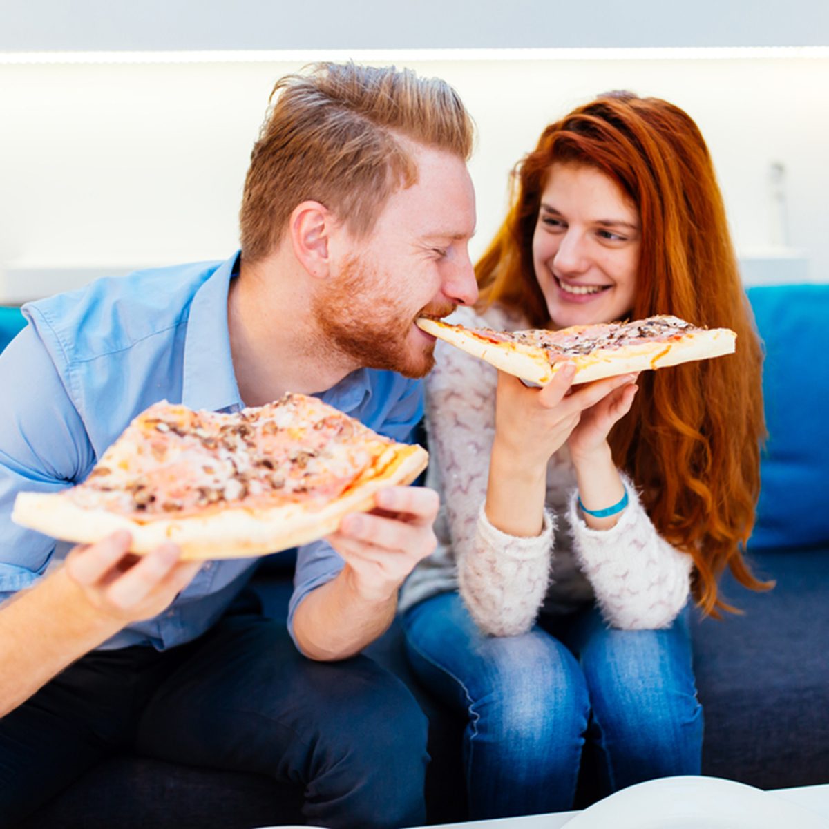 Couple sharing pizza and eating together happily
