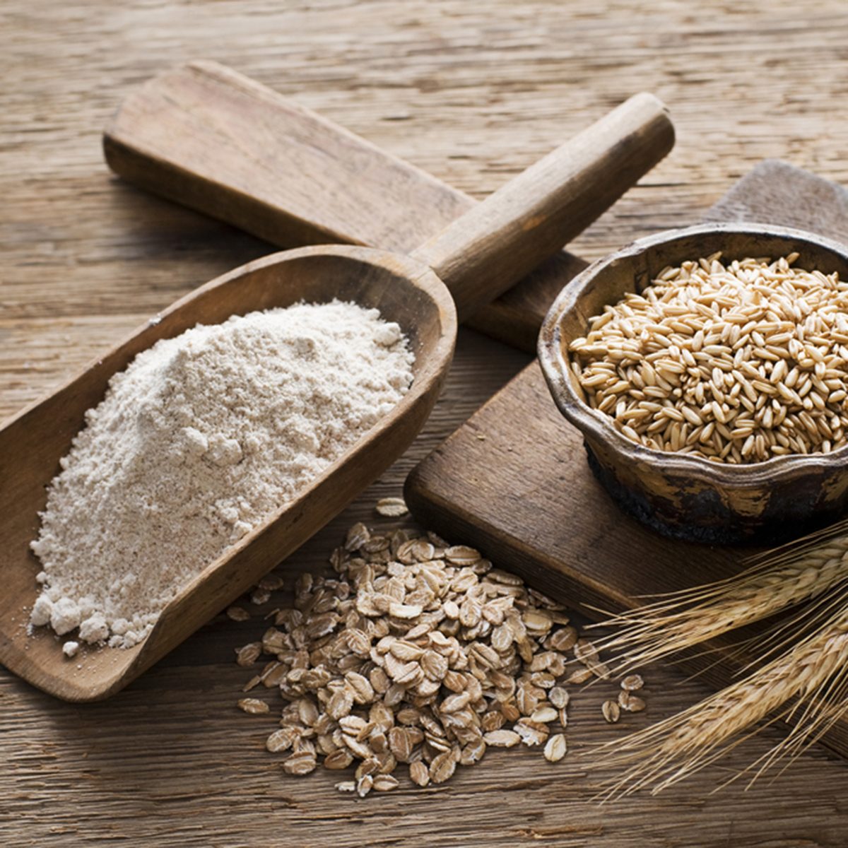 Whole grain and flour on wooden background close up