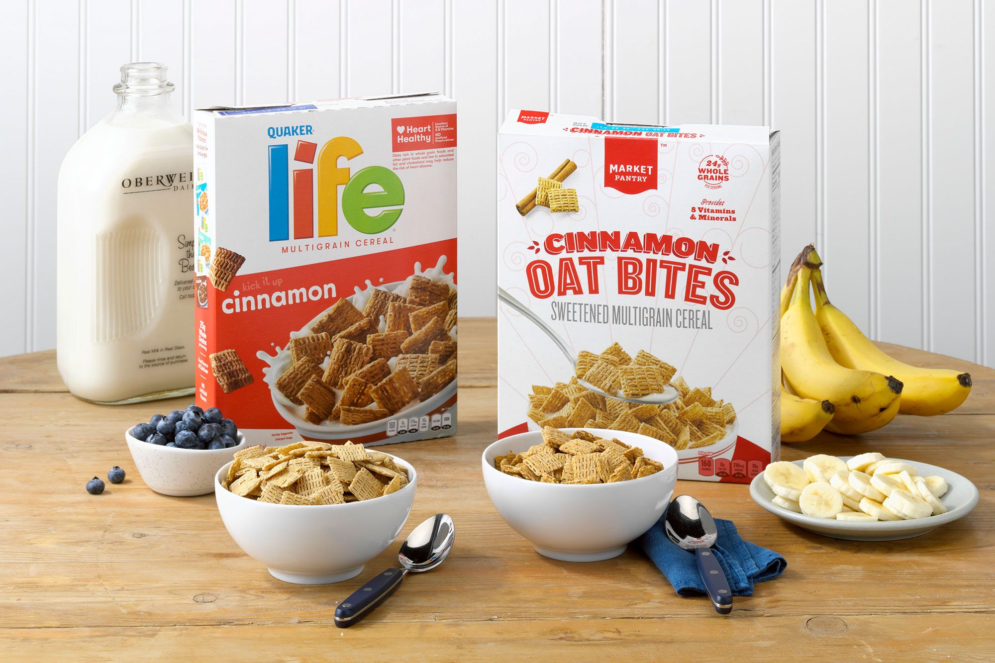 Quaker Life Cinnamon vs. Target's Market Pantry Cinnamon Oat Bites on a wood table with bannanas, blueberries, and milk