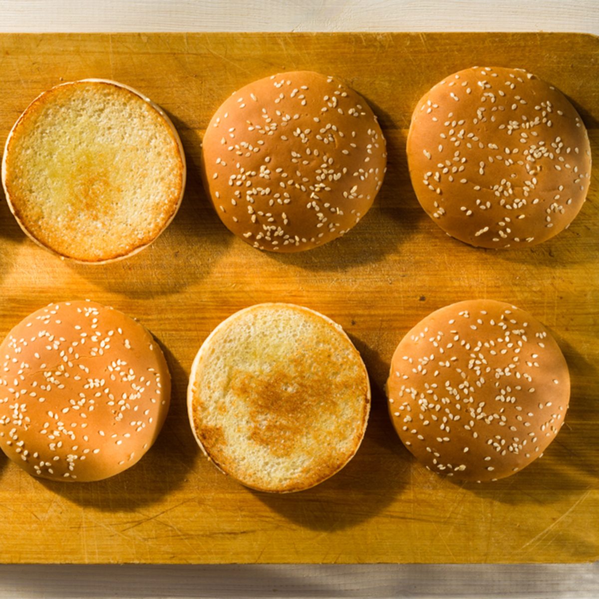 Burger buns with sesame seeds on a chopping board