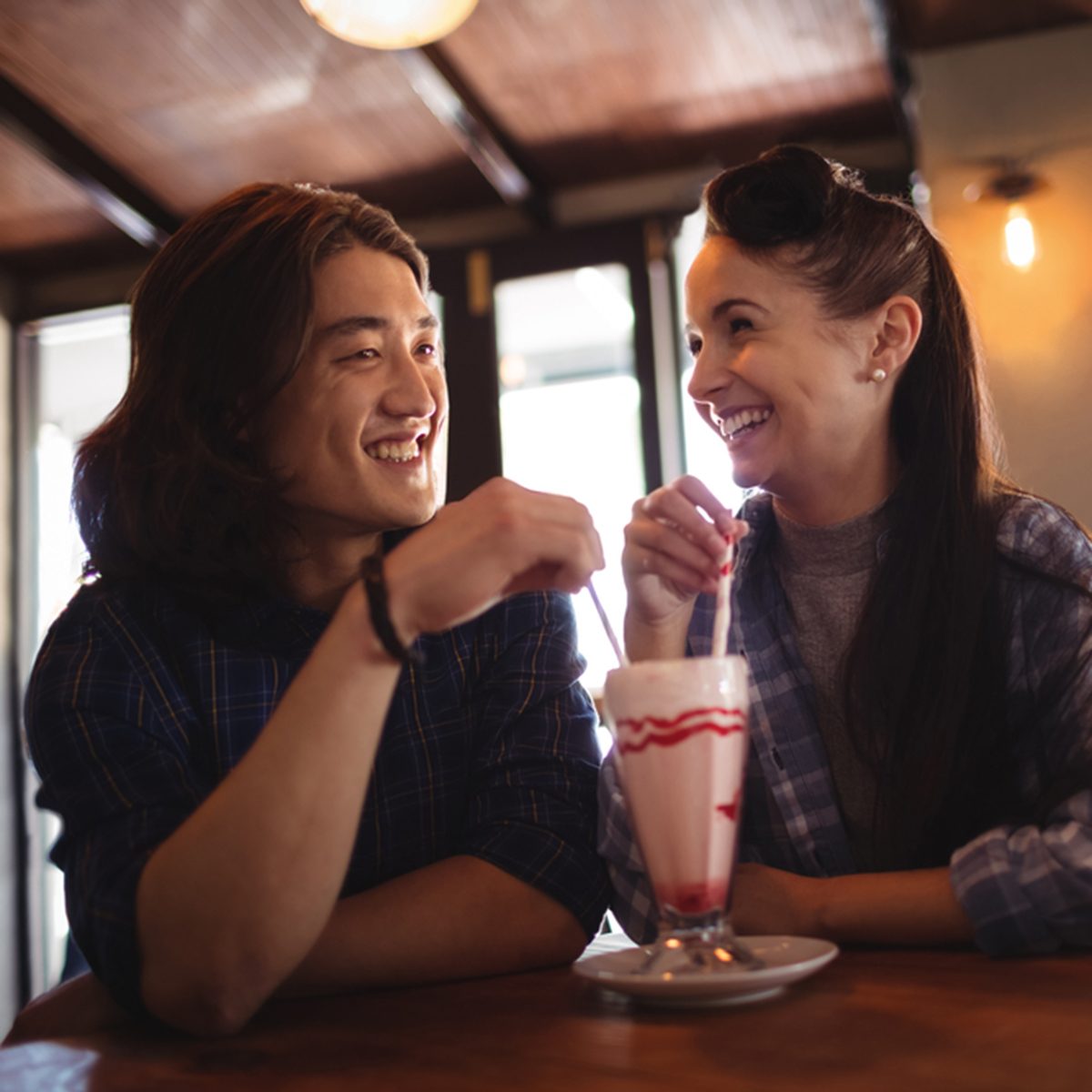 Happy couple having milkshake in restaurant