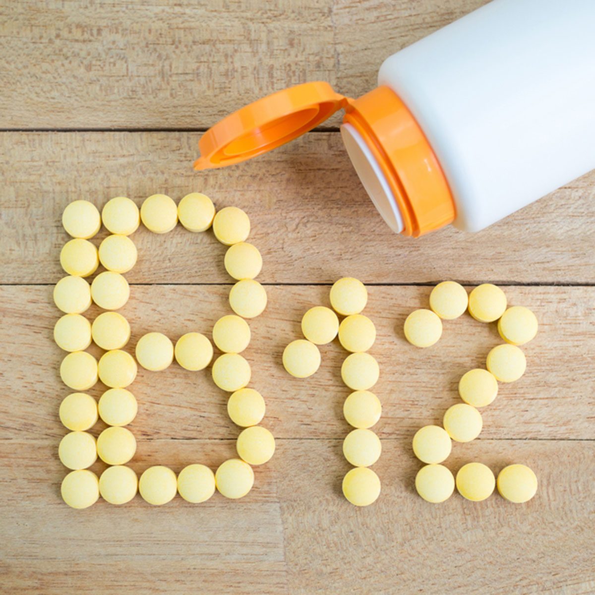 Yellow pills forming shape to B12 alphabet on wood background