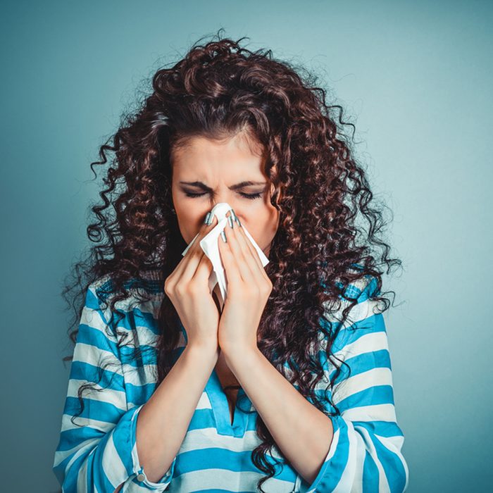 Closeup portrait of woman sneezing or using towel to wipe snot from her nose