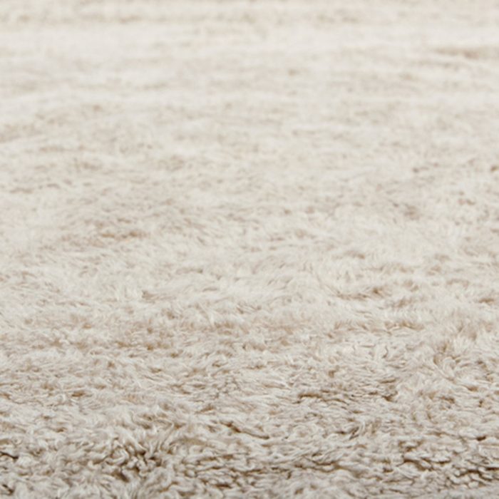 Low close up view of a beige furry carpet texture background