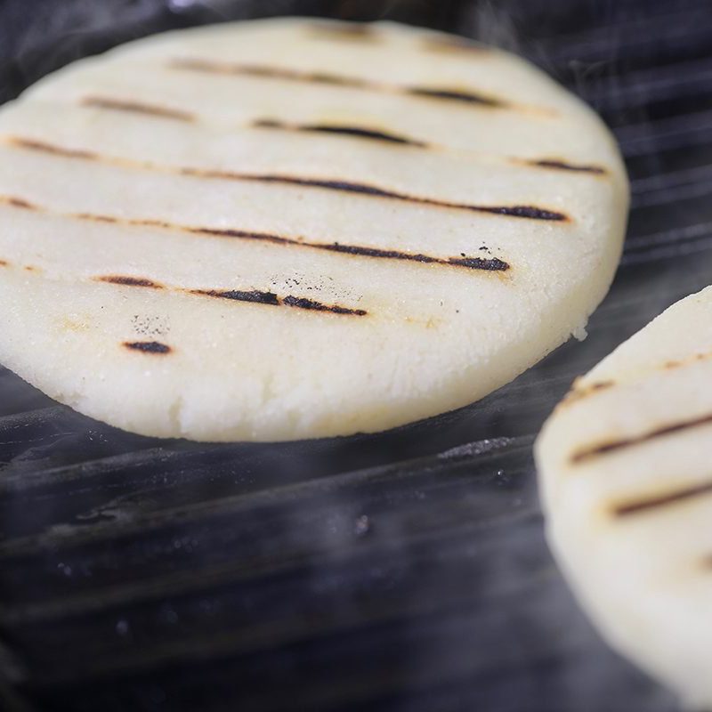 Two arepas on a grill.