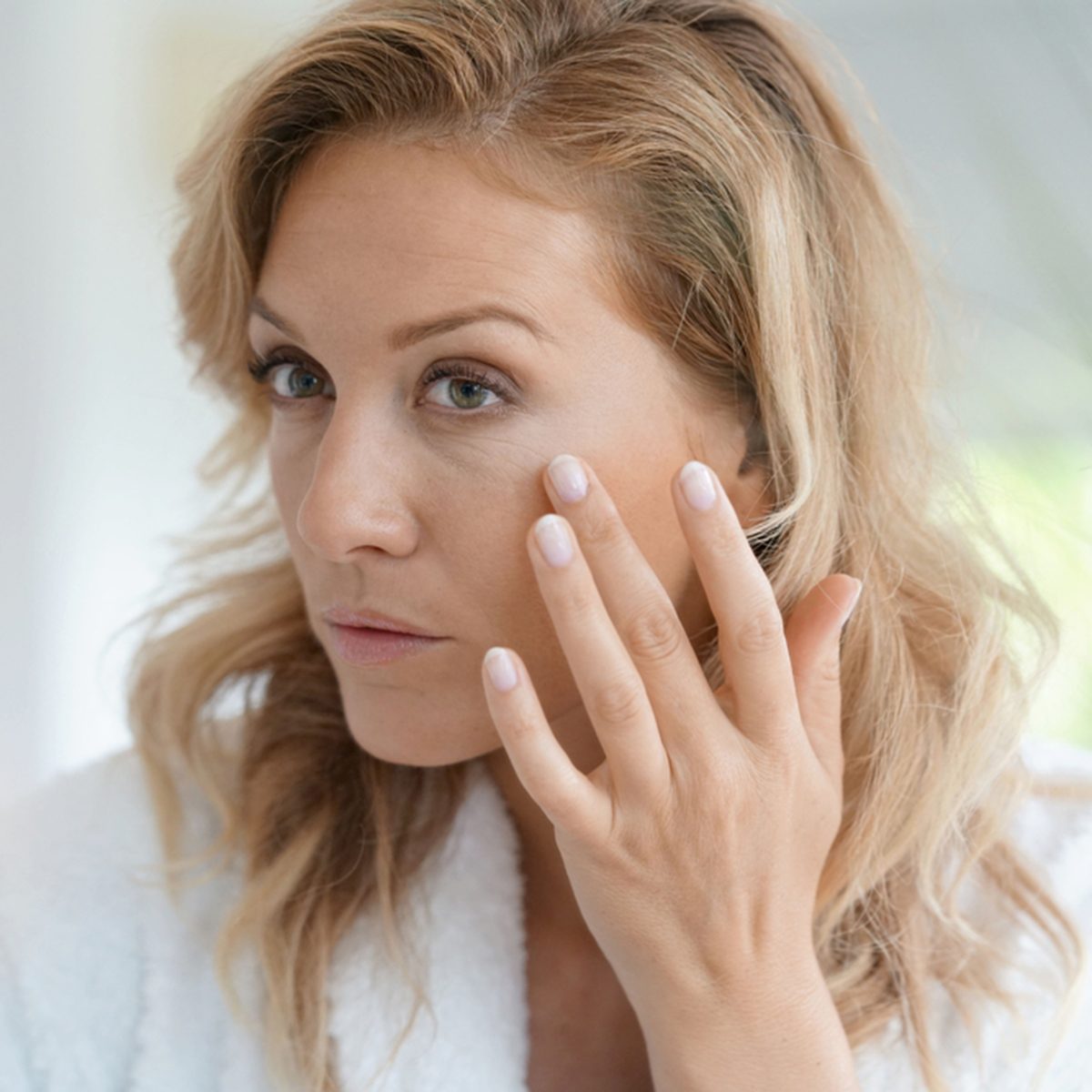 Portrait of attractive blond woman applying anti-aging cream