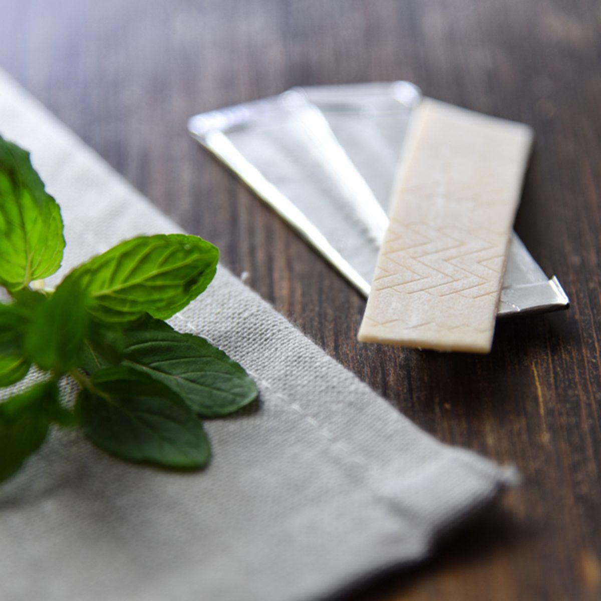 Chewing gums with mint leafs on wooden table