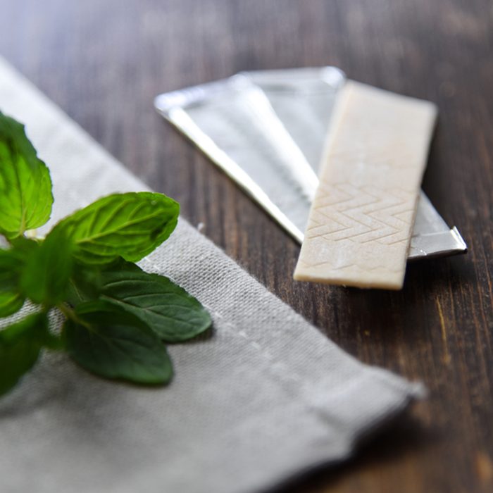 Chewing gums with mint leafs on wooden table