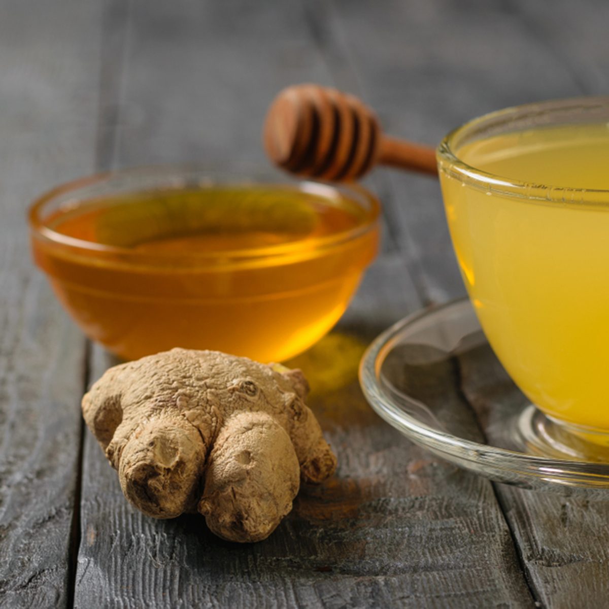 Drink ginger root, lemon, orange, honey and cinnamon on a black wooden table.