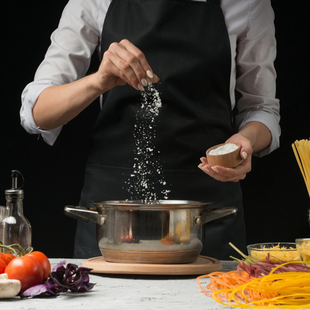 The chef prepares spaghetti and pasta, salt water, against a dark background