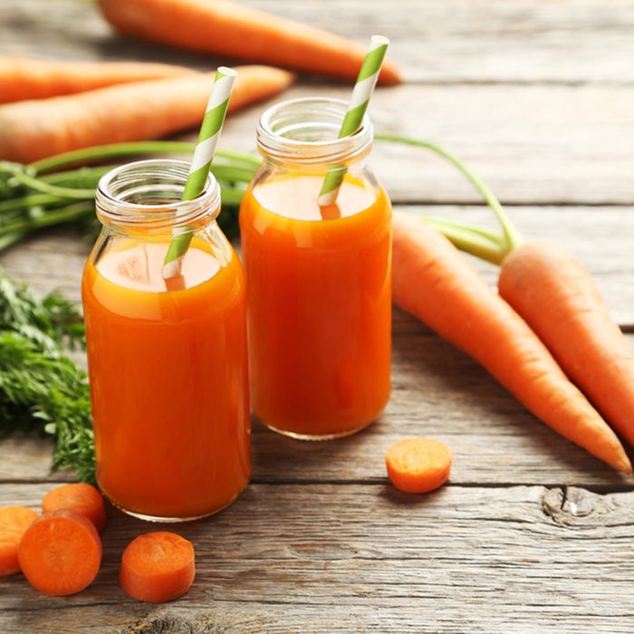 Fresh carrot juice in bottles on a grey wooden table