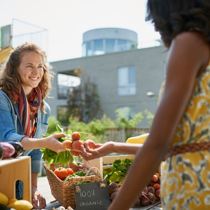 Friendly woman tending an organic vegetable stall at a farmer