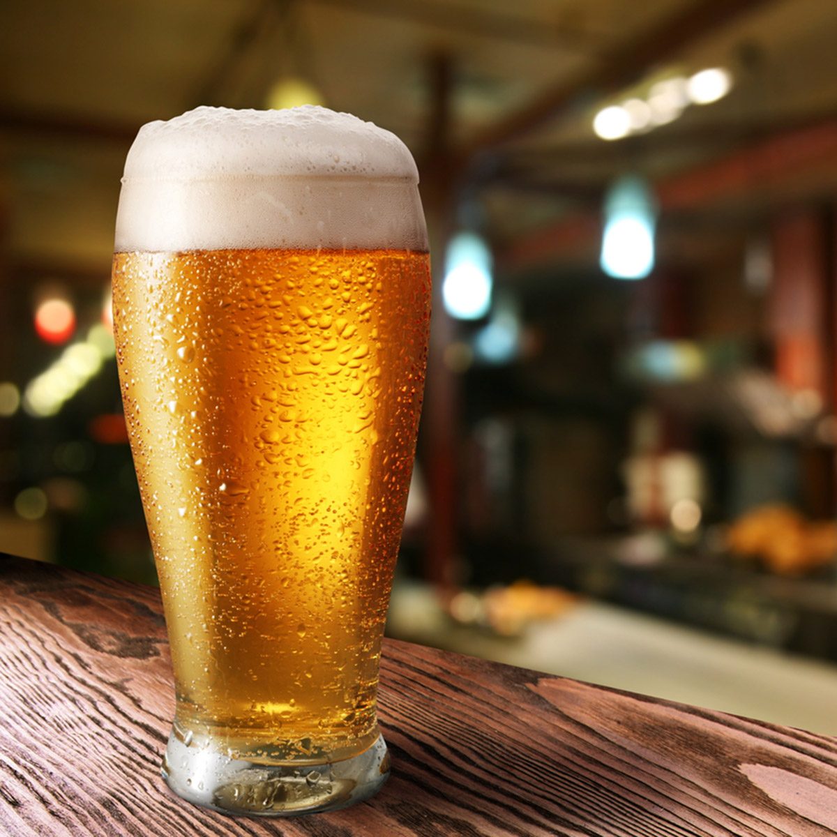 Glass of light beer on a dark pub.