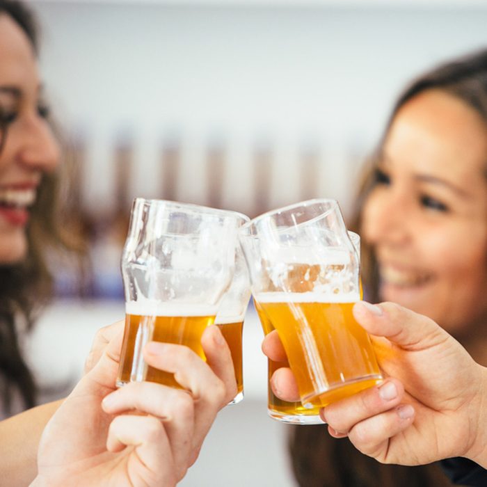Close-up of cheering glasses and two smiling women on background