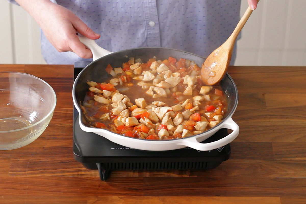 simmering the chicken, broth, and tomatoes for making curry