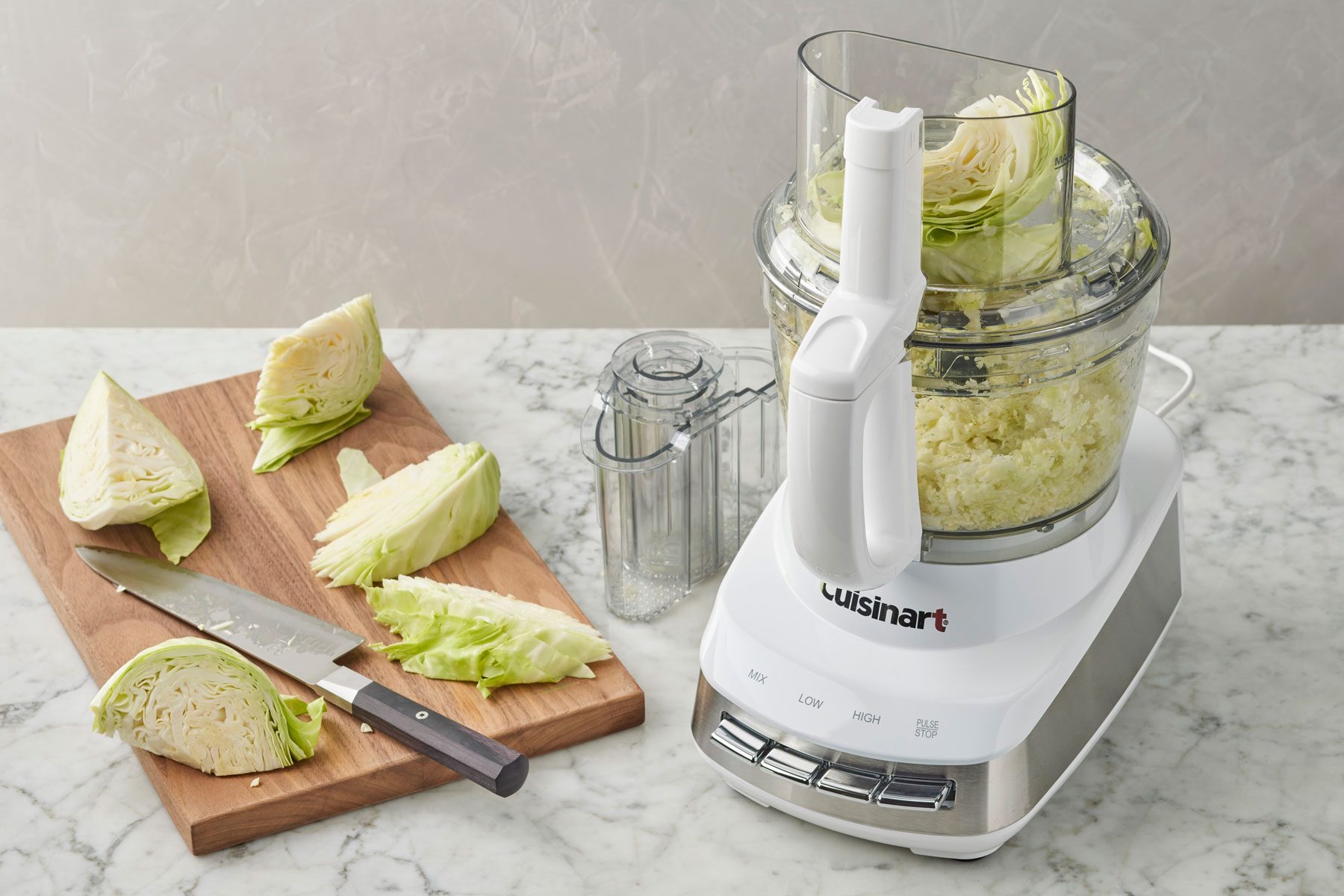 Cabbage In Cuisinart Food Processor With Cutting Board nearby with additional cabbage pieces ready to be loaded into the food processor