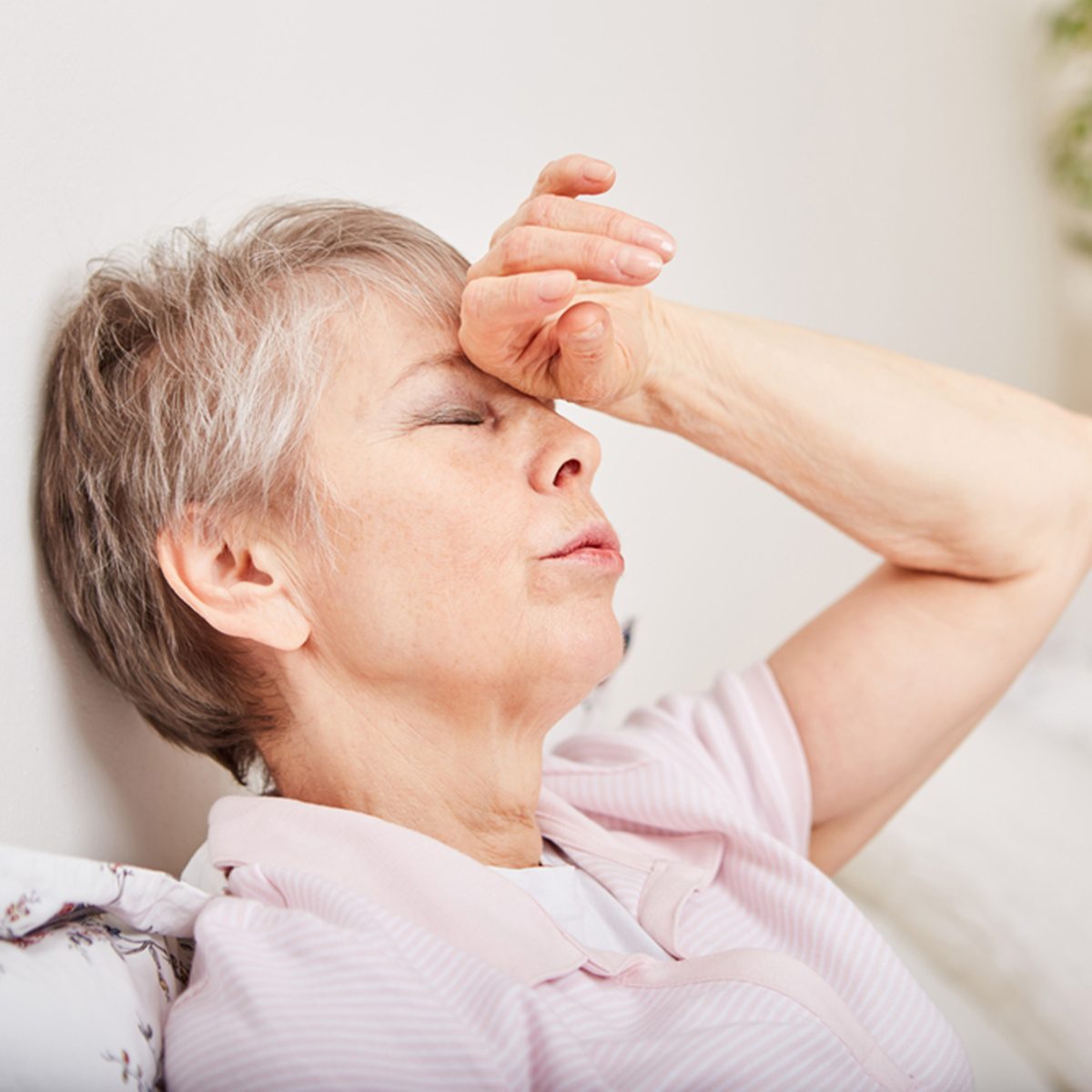 Ill senior woman with headache