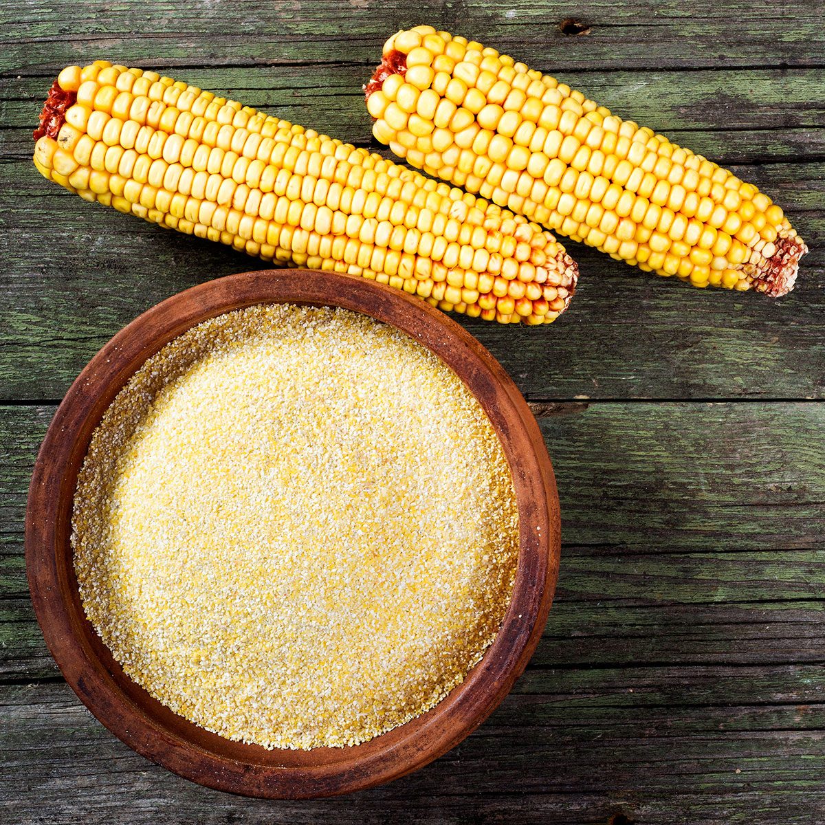 Maize, meal and ceramic bowl on wooden table